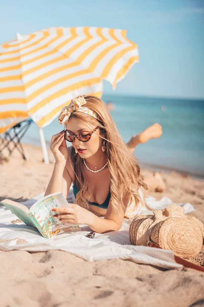 Beautiful lady with beach hair reading a book on the beach